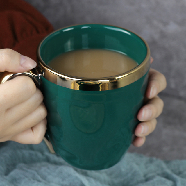 Tasse verte en céramique de cadeau de Noël avec la jante d'or